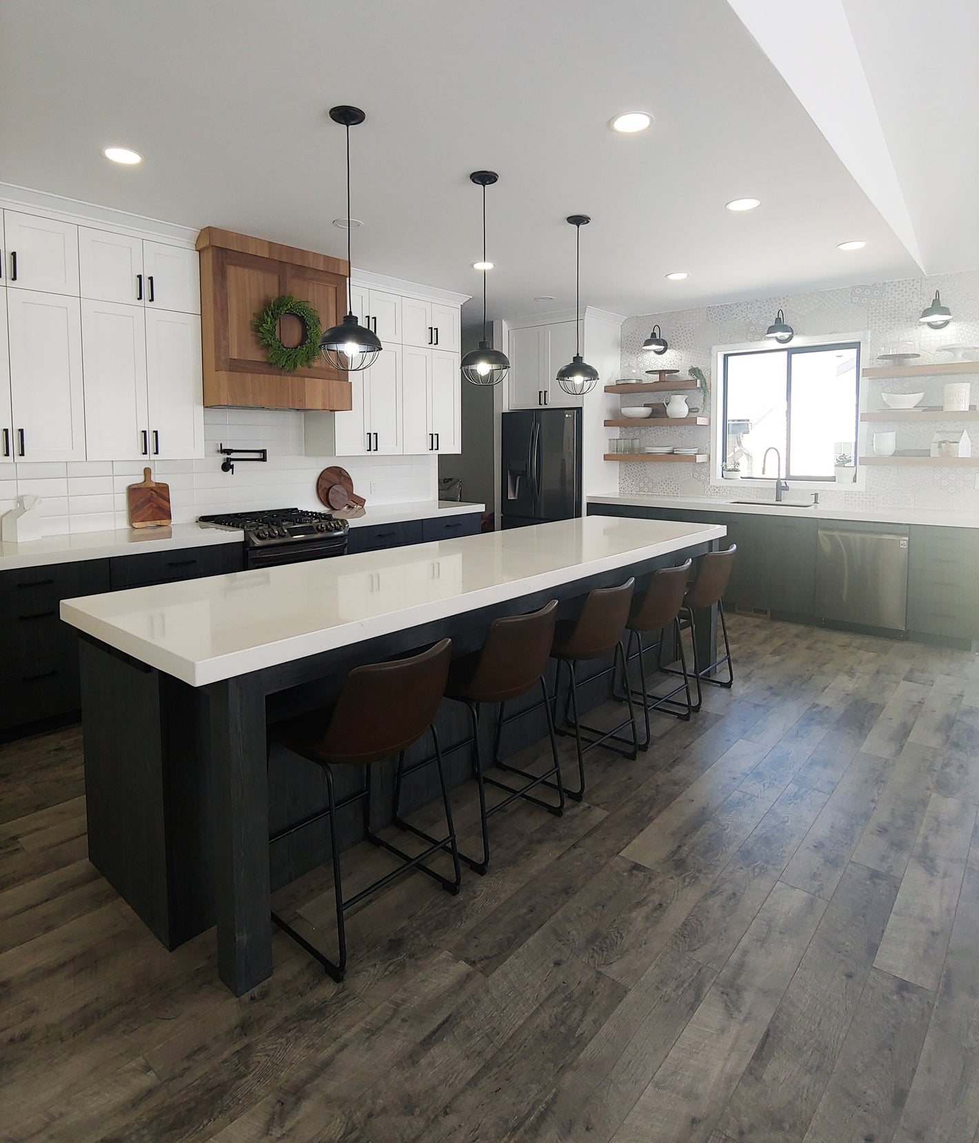 Modern farmhouse kitchen from FARMHOUSE Plan No.6 by Authentic Homes Builder in Utah, featuring a large island, pendant lights, and wood flooring.