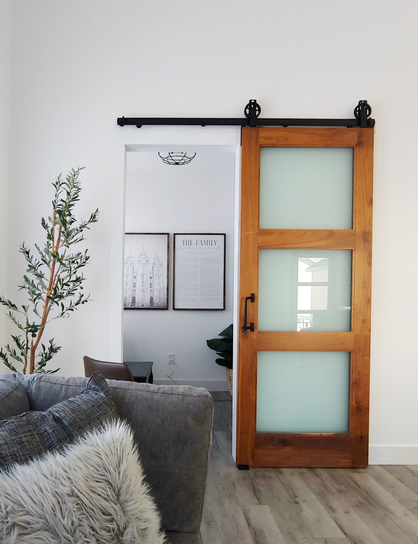 Interior view of FARMHOUSE Plan No.6 featuring a modern sliding barn door with frosted glass panels and natural wood frame, designed by Authentic Homes Builder in Utah.