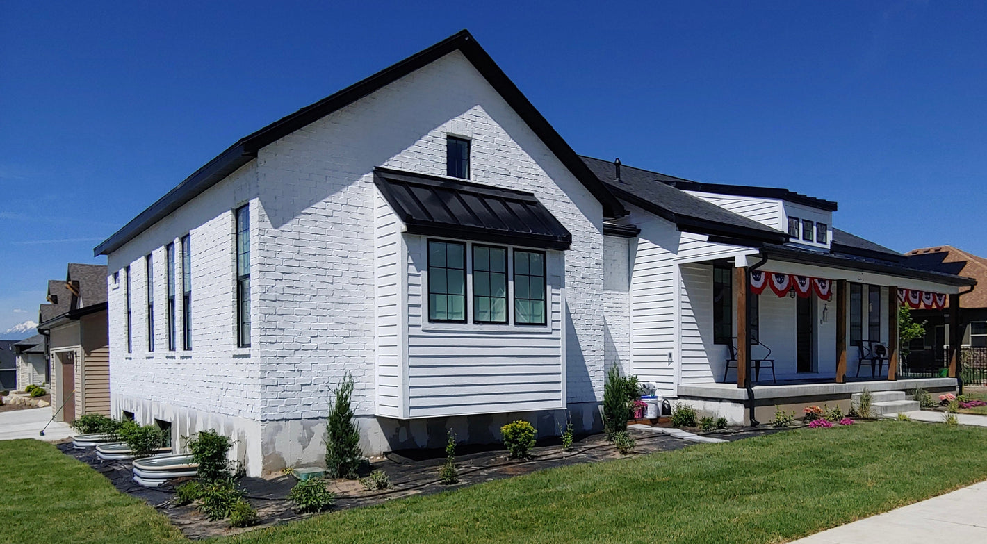 House plan exterior, design by Authentic Homes in Utah. Farmhouse styling with white stucco, siding. Built in Payson, dormer, large porch. White brick.